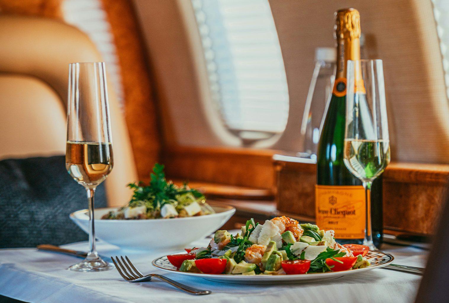 Champagne glasses inside private jet cabin during sunset flight.