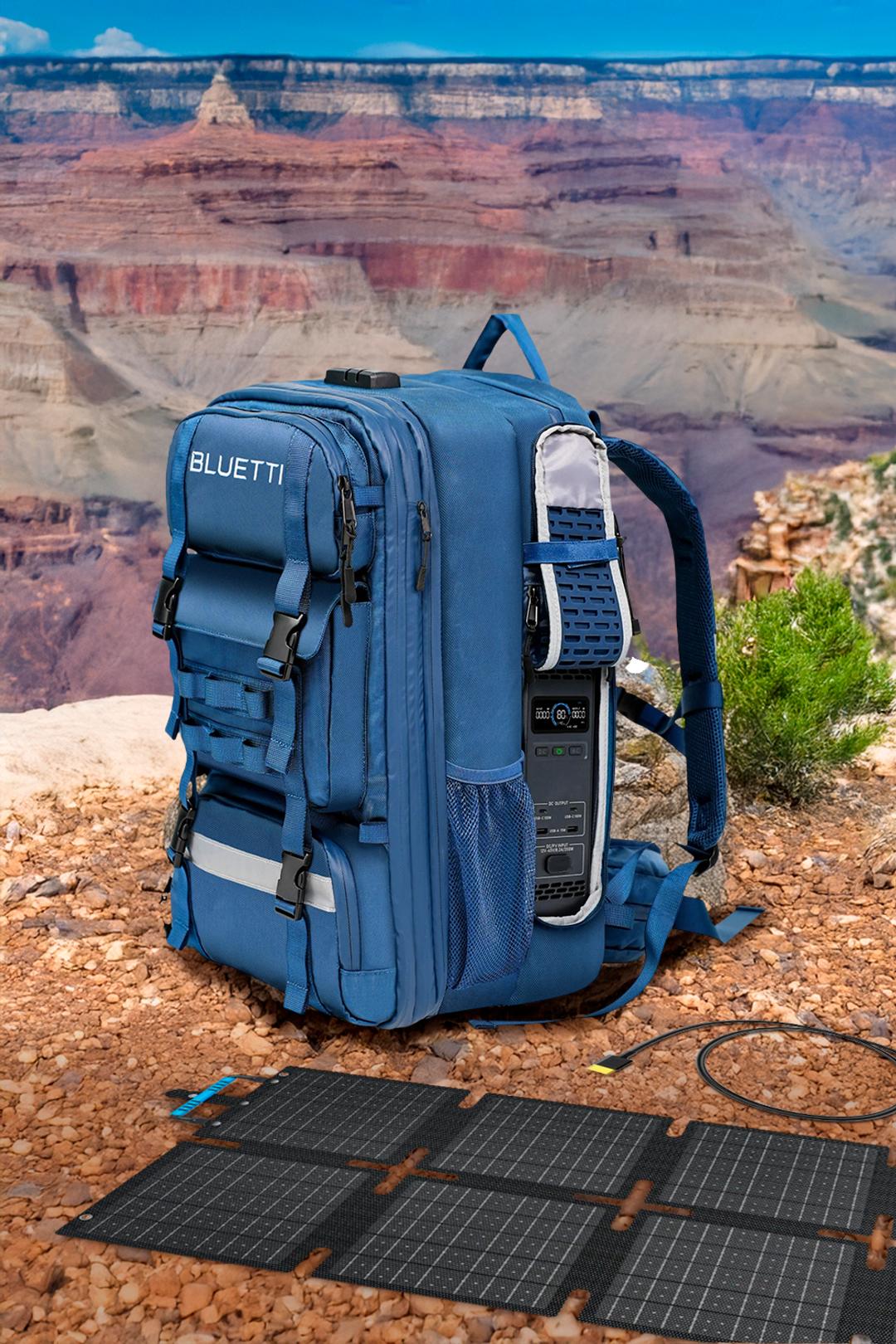 A high-performance blue Bluetti backpack power station sits on a rocky overlook in front of the Grand Canyon, with foldable solar panels spread out on the ground — ideal for off-grid creators, explorers, and power independence.