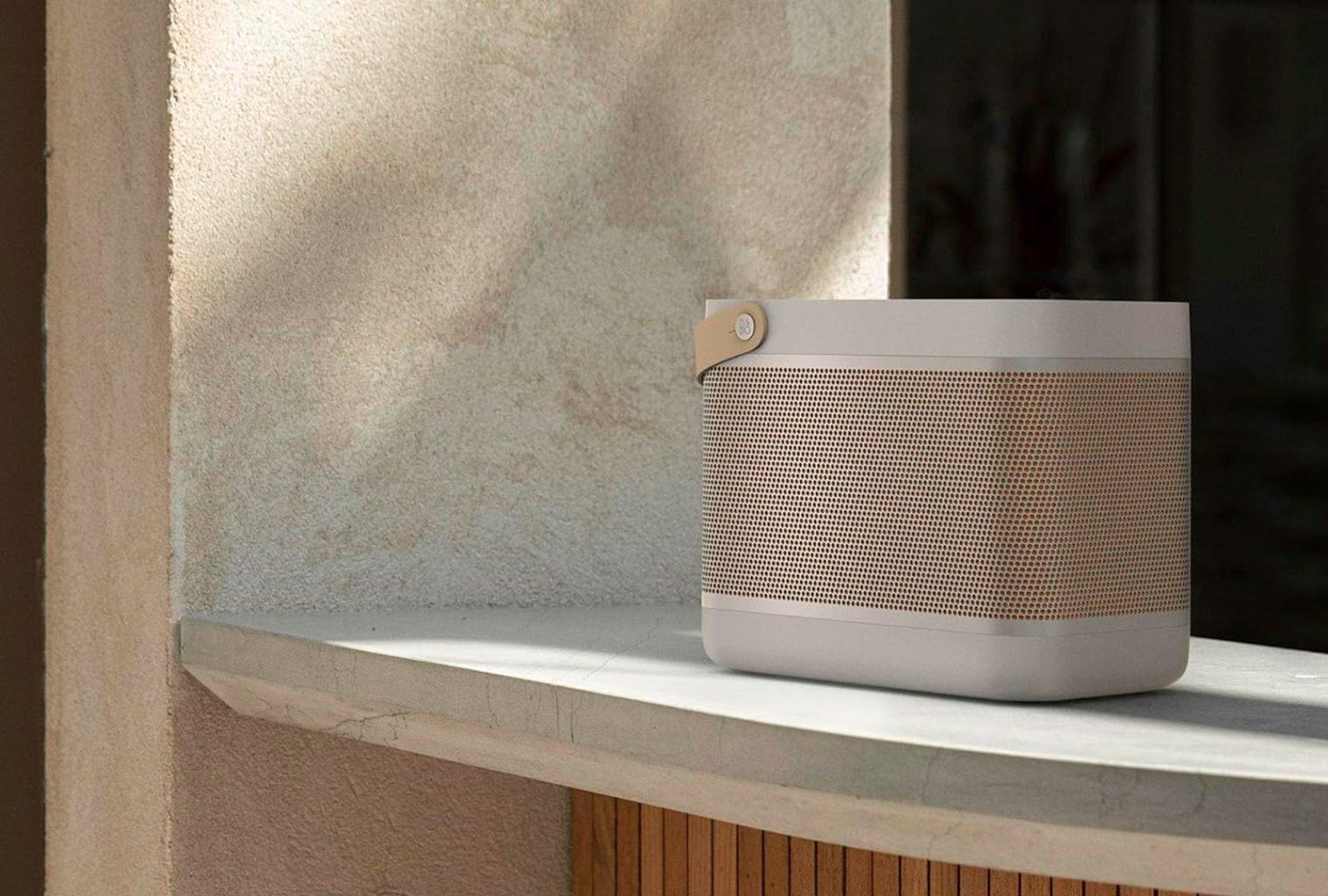 Bang & Olufsen Beolit 20 portable Bluetooth speaker in Grey Mist, styled on a sunlit stone windowsill with soft architectural shadows